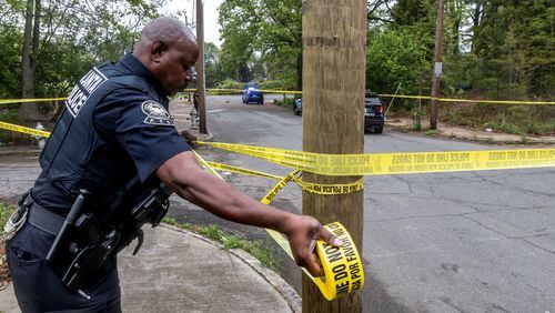 Atlanta police officer R. Mack stretches crime scene tape across Cooper Street on April 10 as police investigate a shooting in southwest Atlanta. (John Spink/The Atlanta Journal-Constitution)