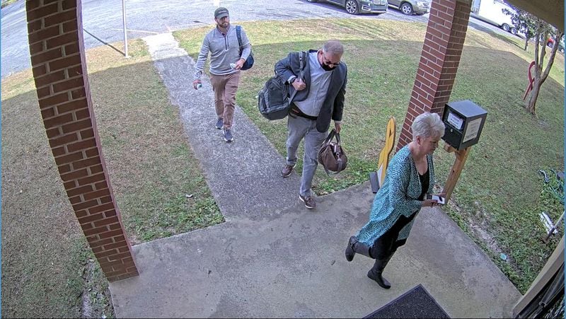 Scott Hall, a bail bondsman who flew from Atlanta to Coffee County and helped coordinate copying of election data, carries bags into the Coffee County elections office on Jan. 7, 2021. He's escorted by Cathy Latham, a fake elector for Donald Trump, and an unidentified man.