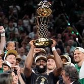 Boston Celtics guard Jaylen Brown, center, holds up the Larry O'Brien Championship Trophy as he celebrates with the team after they won the NBA championship with a Game 5 victory over the Dallas Mavericks, Monday, June 17, 2024, in Boston. (AP Photo/Charles Krupa)