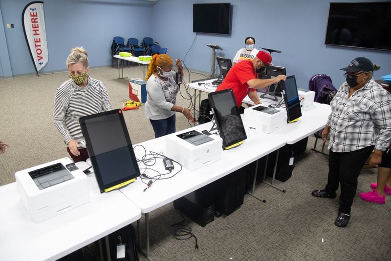 Poll workers unpack voting machines while setting up at the Briarlake Baptist Church polling center in preparation for an election. STEVE SCHAEFER / SPECIAL TO THE AJC 