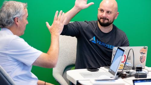 Paul Noble, the founder of Verusen, gets a high five from Jeff Wilson during an afternoon meeting at their Atlanta headquarters several years ago. The company markets AI-driven software used in making supply chains more efficient. STEVE SCHAEFER / SPECIAL TO THE AJC