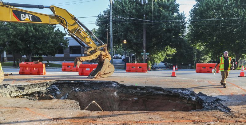 One day after a massive sinkhole opened along one of the most traveled roads in Midtown Atlanta, swallowing an SUV, traffic was moving again on Wednesday, June 28, 2023. Crews were still digging out dirt and temporary roadblocks remain in place on Ponce de Leon Avenue, but at least one eastbound lane and two westbound lanes are open. The portion of road between Myrtle Street and Argonne Avenue had been closed to traffic since Tuesday afternoon to repair a broken sewer pipe that caused the surface to collapse. John Spink / AJC)

