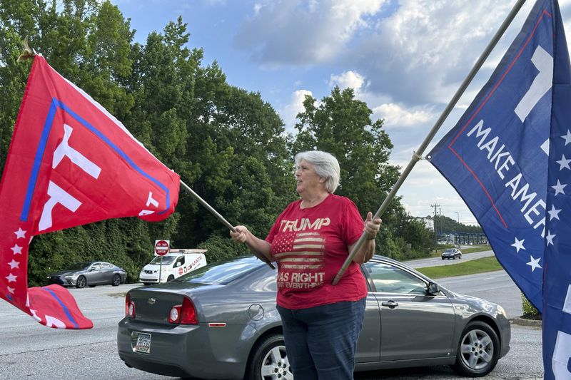 Suzanne Brown waves flags in support of former President Donald Trump before an event in Fayetteville, Ga. 