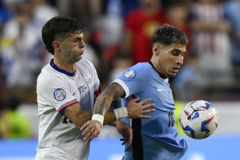 Uruguay's Mathias Olivera, right, controls the ball challenged by Christian Pulisic of the United States during a Copa America Group C soccer match in Kansas City, Mo., Monday, July 1, 2024. (AP Photo/Reed Hoffman)