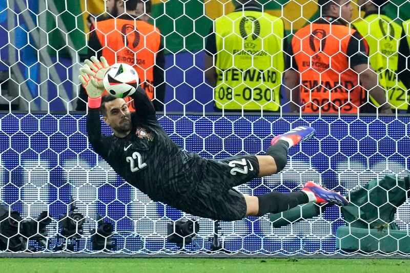 Portugal's goalkeeper Diogo Costa saves the ball during penalties of a round of sixteen match between Portugal and Slovenia at the Euro 2024 soccer tournament in Frankfurt, Germany, Monday, July 1, 2024. (AP Photo/Ebrahim Noroozi)