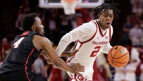 Oklahoma guard Javian McCollum (2) is defended by Houston guard L.J. Cryer (4) during the second half of an NCAA college basketball game Saturday, March 2, 2024, in Norman, Okla. (AP Photo/Garett Fisbeck)