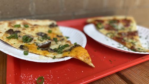 Old Fourth Ward pizzeria Glide sells slices of its massive, 20-inch Brooklyn-style pies, including the Homegrown (left) featuring pimento cheese. Ligaya Figueras/ligaya.figueras@ajc.com