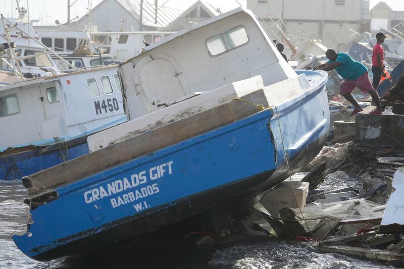 A fisherman pushes a boat damaged by Hurricane Beryl at the Bridgetown Fisheries in Barbados, Monday, July 1, 2024. (AP Photo/Ricardo Mazalan)