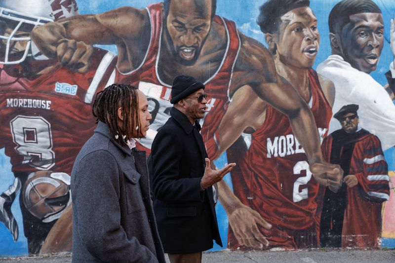 (Left to right) Morehouse student and AJC intern Auzzy Byrdzell chats with Morehouse alumnus and Olympian Edwin Moses while walking in front of a mural featuring Moses on Wednesday, Jan. 17, 2024. (Natrice Miller/ Natrice.miller@ajc.com)