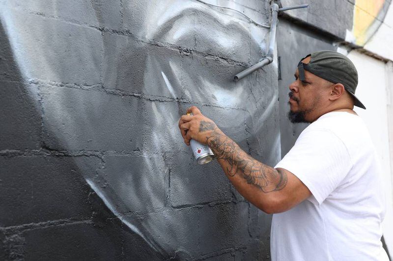 Kevin “Scene” Lewis touches up his mural of civil rights leader John Lewis on Monday, June 24, 2024, off of South Commercial Circle in Warner Robbins, Georgia. Lewis repainted parts of the mural after it was defaced. (Photo Courtesy of Katie Tucker/The Telegraph)