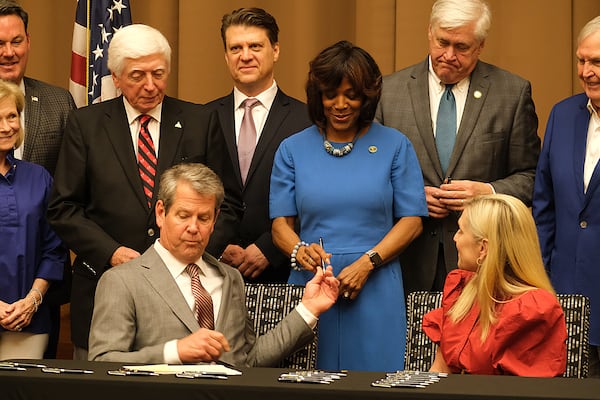 Gov. Brian Kemp hands a ceremonial pen to Morehouse Medical School President Valerie Montgomery Rice during a signing ceremony on Friday.