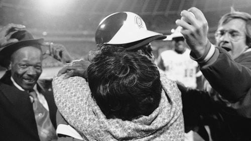 Atlanta Braves' Hank Aaron is embraced by his mother, Estella, as his father Herbert, left, nearly loses his hat and Braves pitcher Tommy House holds the ball that Aaron hit to break Babe Ruth's record, April 8, 1974, in Atlanta.  (AP Photo)